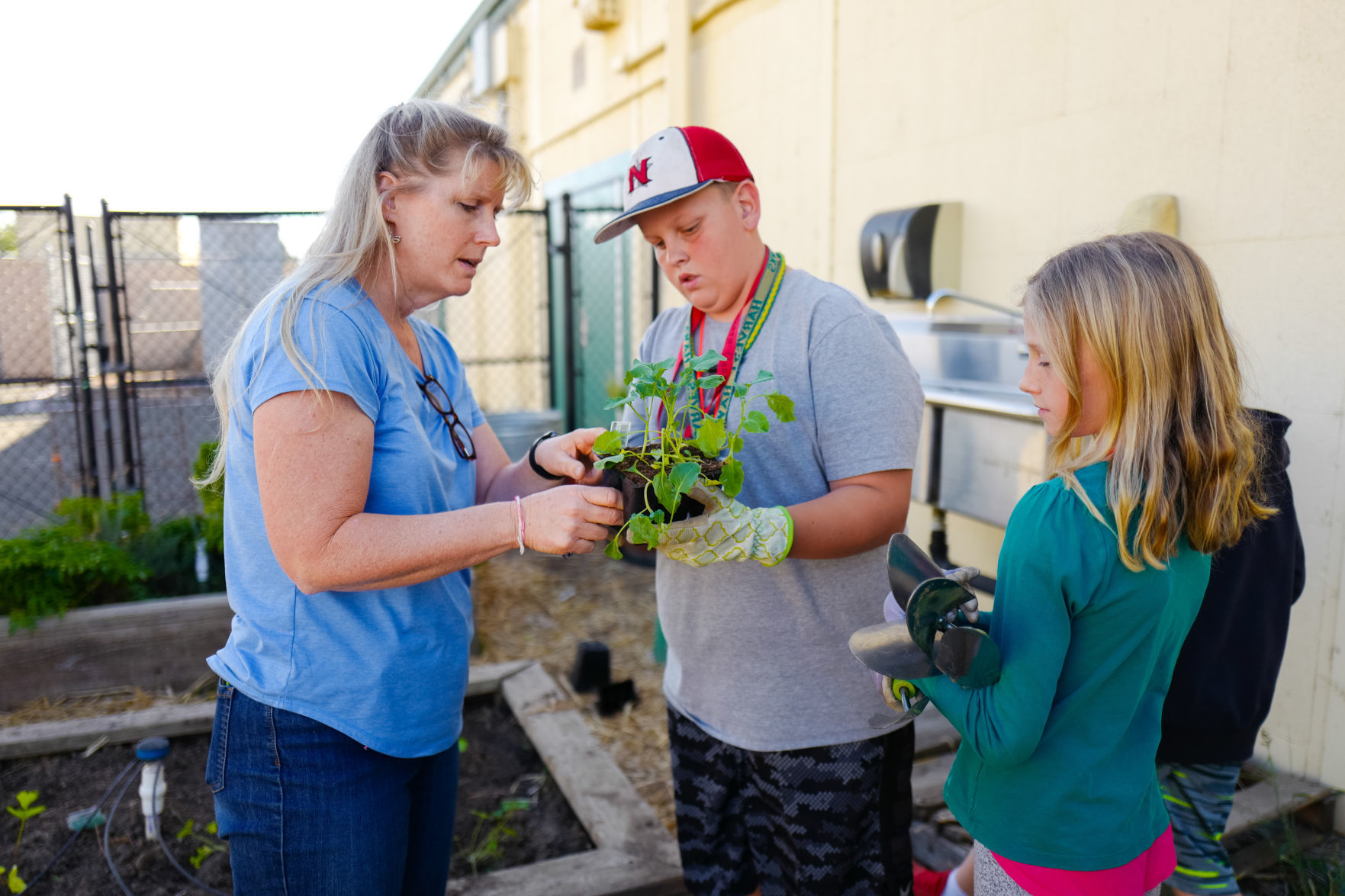 HMS teacher Karen Fleming and students Jake Newman and Cadence Hughes inspect a broccoli plant